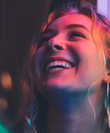 Girl smiling showing teeth in neon lights