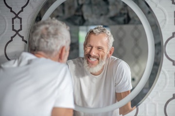 man looking in the mirror at dental hygiene